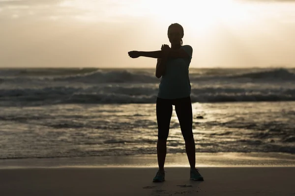 Sportliche Brünette Stretching am Strand — Stockfoto