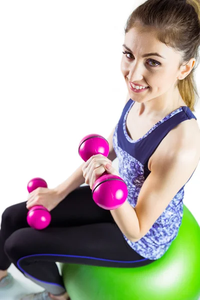 Fit woman lifting dumbbell on ball — Stock Photo, Image