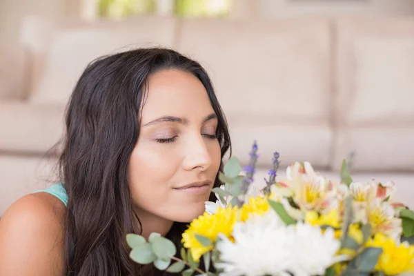 Mooie brunette liggend op de vloer en ruiken de bloemen — Stockfoto