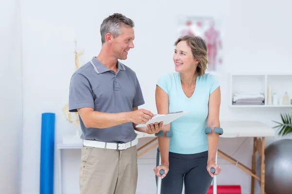 Woman using crutch and talking with her doctor — Stock Photo, Image