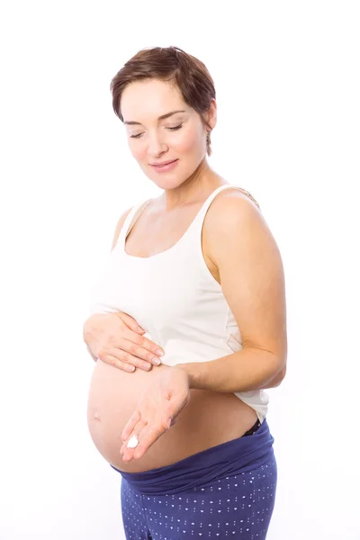 Femme enceinte montrant crème pour le corps — Photo