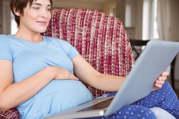 Беременная женщина пользуется ноутбуком — стоковое фото