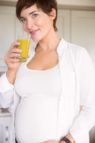 Mujer embarazada bebiendo un vaso de jugo de naranja —  Fotos de Stock