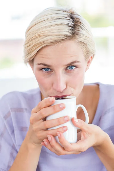 Blonde vrouw op de Bank bezit een mok — Stockfoto