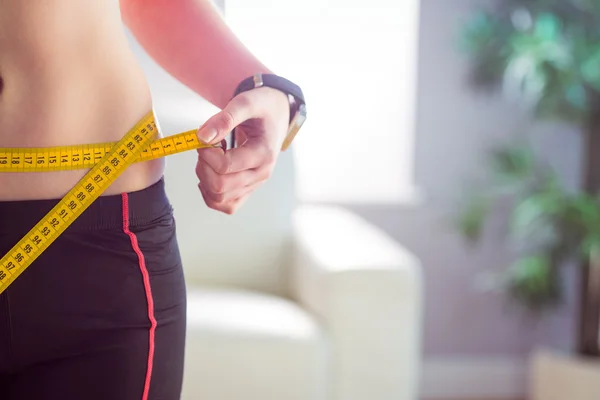 Slim woman measuring waist with tape measure — Stock Photo, Image