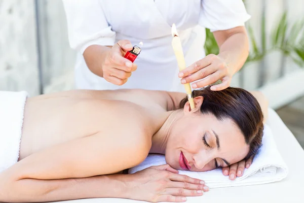 Relaxed brunette getting an ear candling treatment — Stock Photo, Image