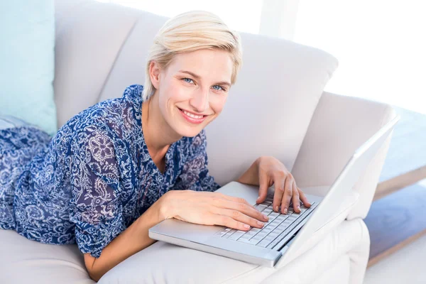 Mulher loira no sofá usando laptop — Fotografia de Stock