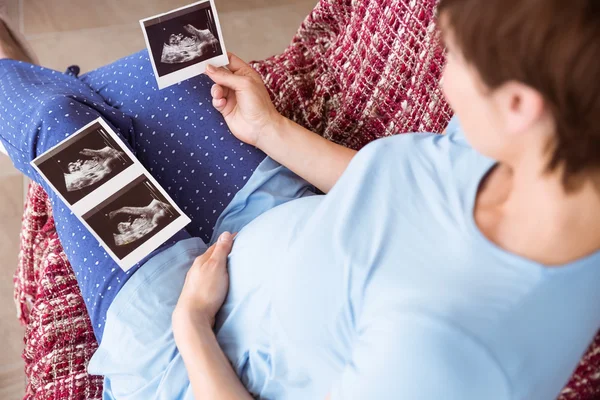 Těhotná žena při pohledu na ultrazvukové vyšetření — Stock fotografie