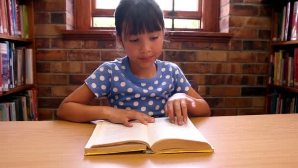 Söta eleven läsa en bok på biblioteket — Stockvideo