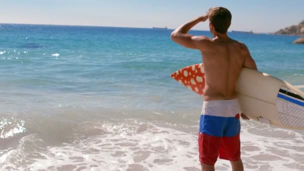 Красивий чоловік стоїть з дошкою для серфінгу — стокове відео