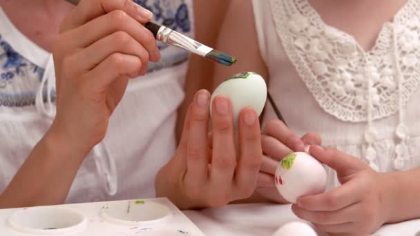 Счастливая мать и дочь рисуют пасхальные яйца — стоковое видео