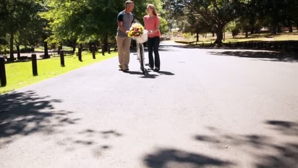 Lyckliga par promenader med cykel och blombukett — Stockvideo