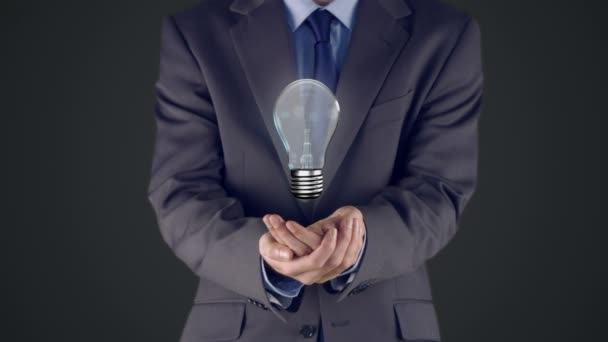Empresário apresentando lâmpada com as mãos — Vídeo de Stock