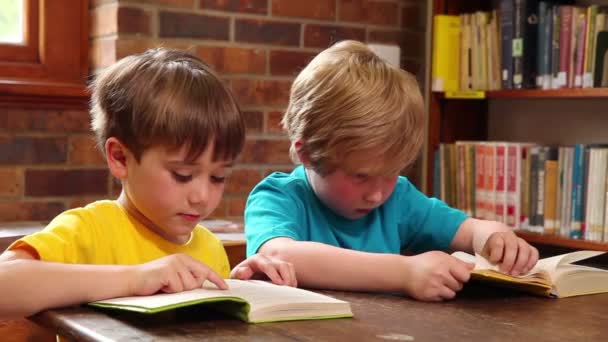 Симпатичные ученики читают в библиотеке — стоковое видео