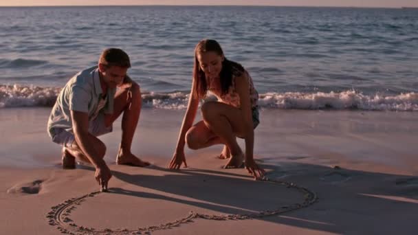 Щаслива пара малює серце в піску — стокове відео