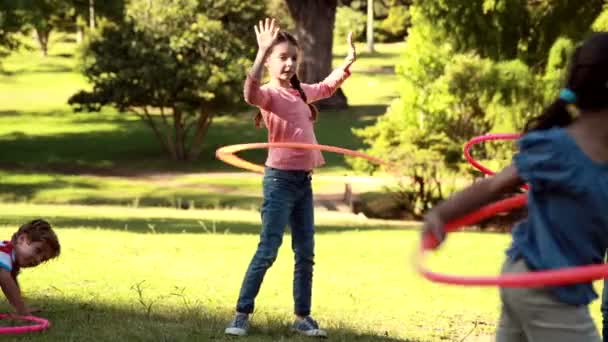 Little friends playing with hula hoops in park — Stock Video