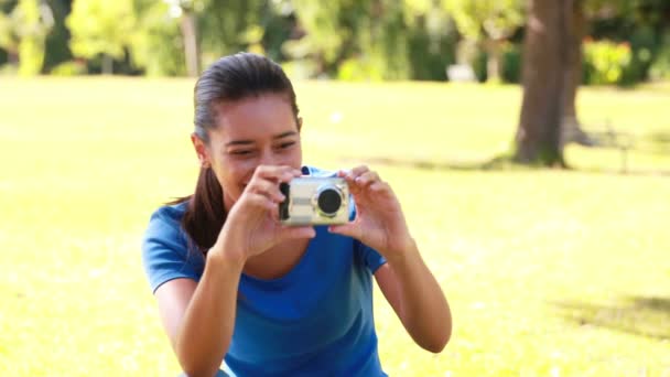 Усміхнена брюнетка фотографує в парку — стокове відео