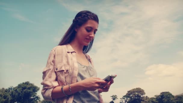 Pretty brunette texting in the park — Stock Video