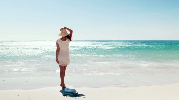 Frau in weißem Kleid spaziert am Strand — Stockvideo