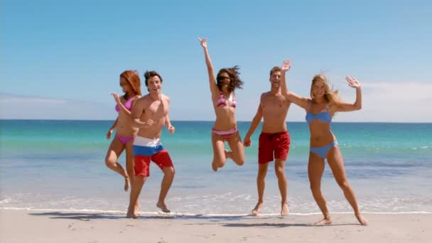 Amigos felices saltando en la playa — Vídeo de stock