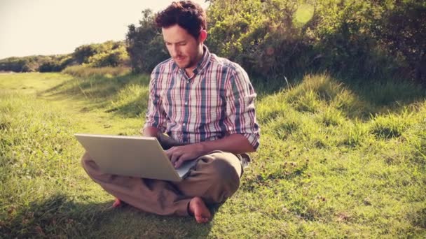 Joven usando laptop en el campo — Vídeos de Stock