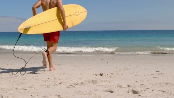Красивый мужчина, бегущий в воде с доской для серфинга — стоковое видео
