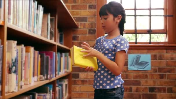 Źrenica biorąc książkę z półki w bibliotece — Wideo stockowe