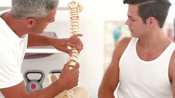 Médico mostrando modelo de columna vertebral al paciente — Vídeos de Stock