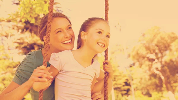 Mother pushing her daughter on a swing — Stock Photo, Image