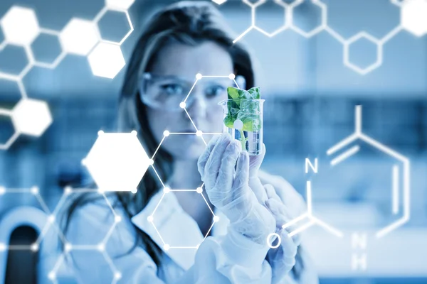 Woman standing at the laboratory holding a glass — Stock fotografie