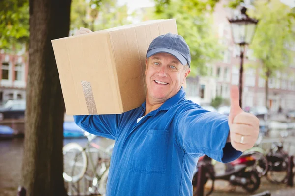 Sammansatt bild av glad leverans mannen hålla kartong — Stockfoto