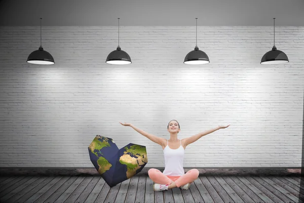 Woman sitting with arms raised against grey room — Stock Photo, Image