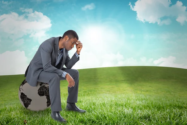 Denkender Geschäftsmann sitzt gegen Feld — Stockfoto