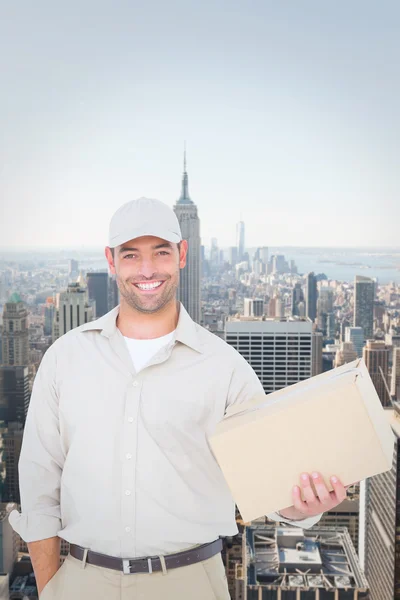Composite image of handsome delivery man with cardboard box on w — Stock Photo, Image