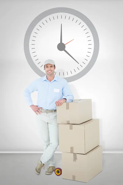 Delivery man leaning on stacked cardboard boxes — Stock Photo, Image