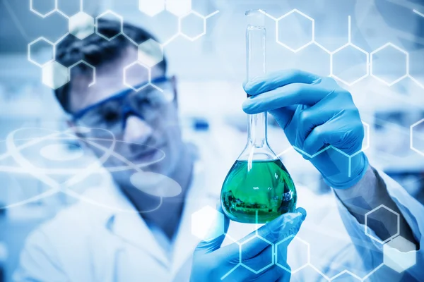 Химик держит стакан зеленого химиката — стоковое фото