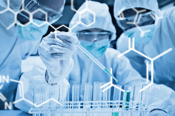 Chemist adding green liquid to test tubes — Stock Photo, Image