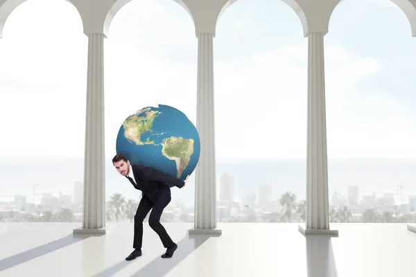 Empresário carregando o mundo contra colunas — Fotografia de Stock