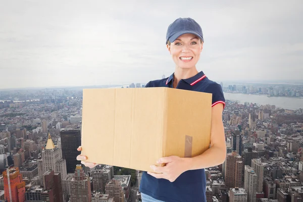 Композитное изображение счастливой курьерши, держащей картонную коробку — стоковое фото