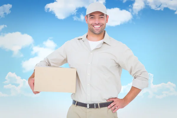 Composite image of confident delivery man with cardboard box on — Stock Photo, Image