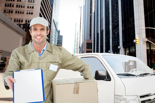 Happy delivery man with box showing clipboard — Stock Photo, Image