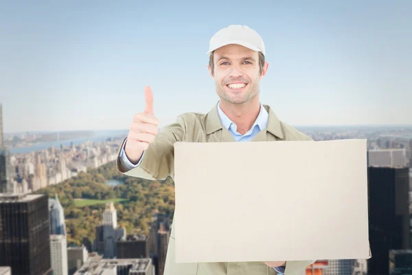 Composite image of happy delivery man gesturing thumbs up while — Stock Photo, Image