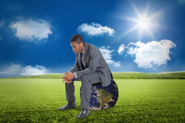 Thinking businessman sitting against sunny landscape — Stock Photo, Image