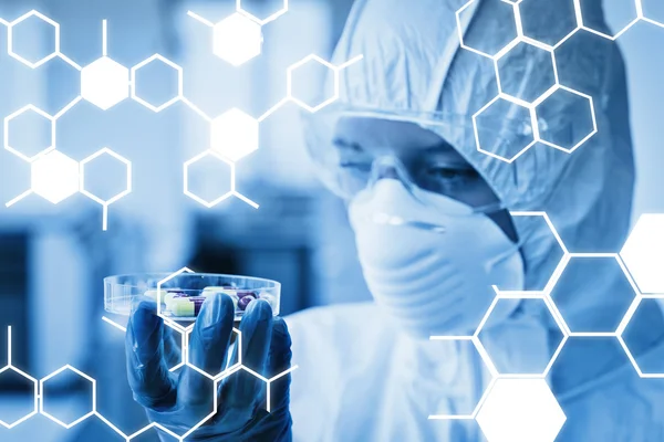 Scientist in protective suit analyzing pills — Stock Photo, Image