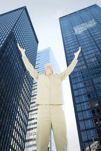 Composite image of excited delivery man with arms raised looking — Stock Photo, Image