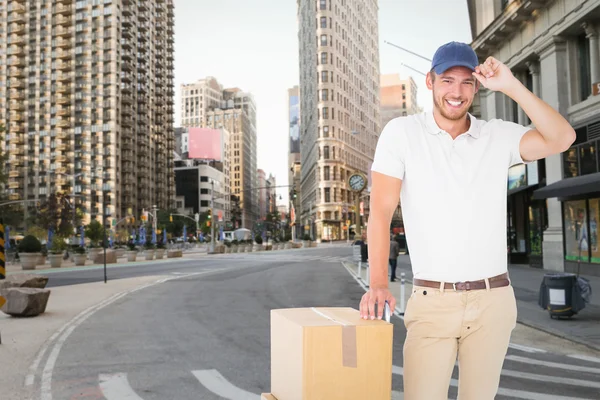 Composite image of happy delivery man leaning on trolley of boxe — Stock Photo, Image