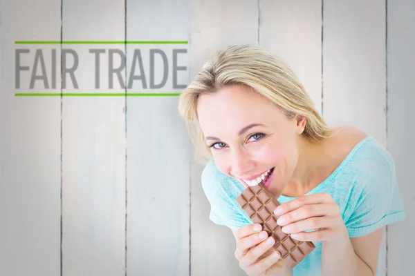 Composite image of pretty blonde eating bar of chocolate — Stock fotografie