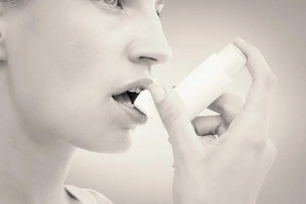 Imagen compuesta de una mujer rubia tomando su inhalador — Foto de Stock