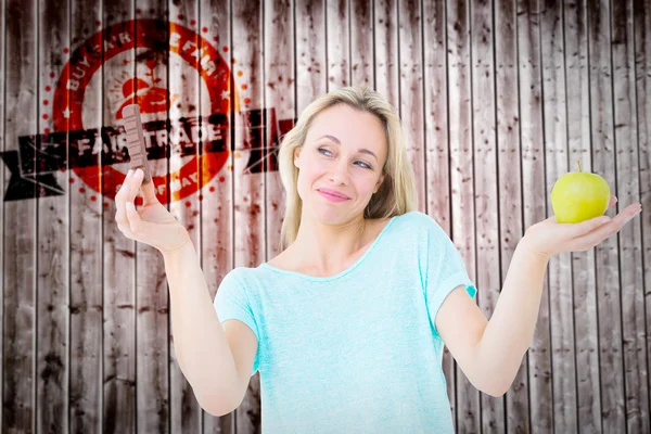 Composite image of smiling blonde holding bar of chocolate and a — Stockfoto