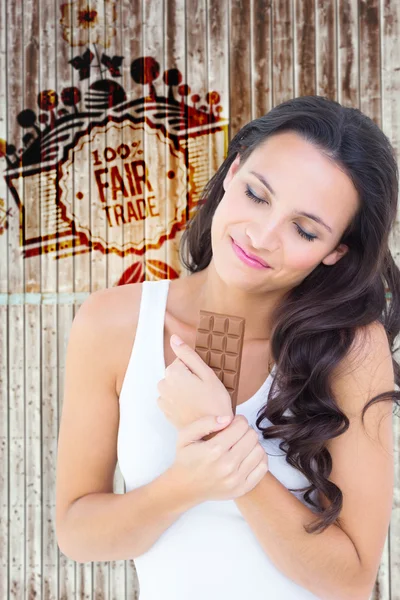 Composite image of pretty brunette eating bar of chocolate — ストック写真